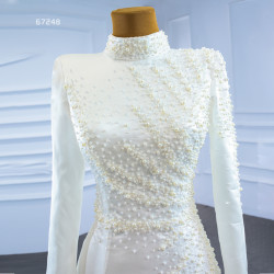 فستان زفاف فاخر وعصري بلون العاج بياقة عالية وأكمام طويلة بتصميم حورية البحر وذيل قابل للفصل ومطرز بالدانتيل والزهور