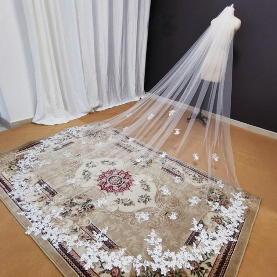 A long embroidered tulle wedding veil from Koshin adorned with flowers and lace in a modern design